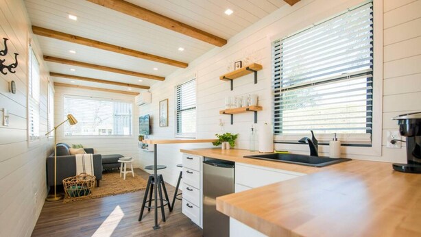A modern kitchen with wooden beams, white cabinetry, and a central island. - Pecan Grove Container Tiny Home Country Setting 12 min to Baylor Magnolia (Waco)