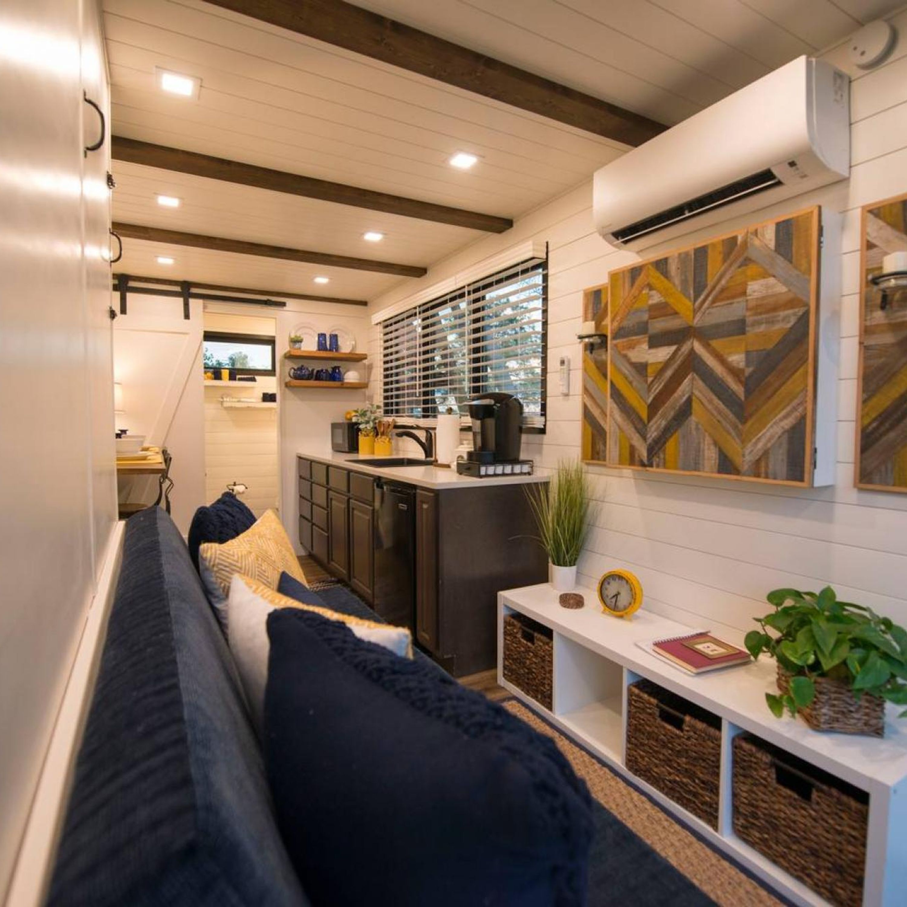 A compact living space with a sofa, a kitchenette, and a decorative wall piece.