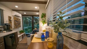 A modern kitchen with a wooden countertop, a dining table, and a window with blinds. - Yellow Blue Elegant Container Tiny House (Waco)