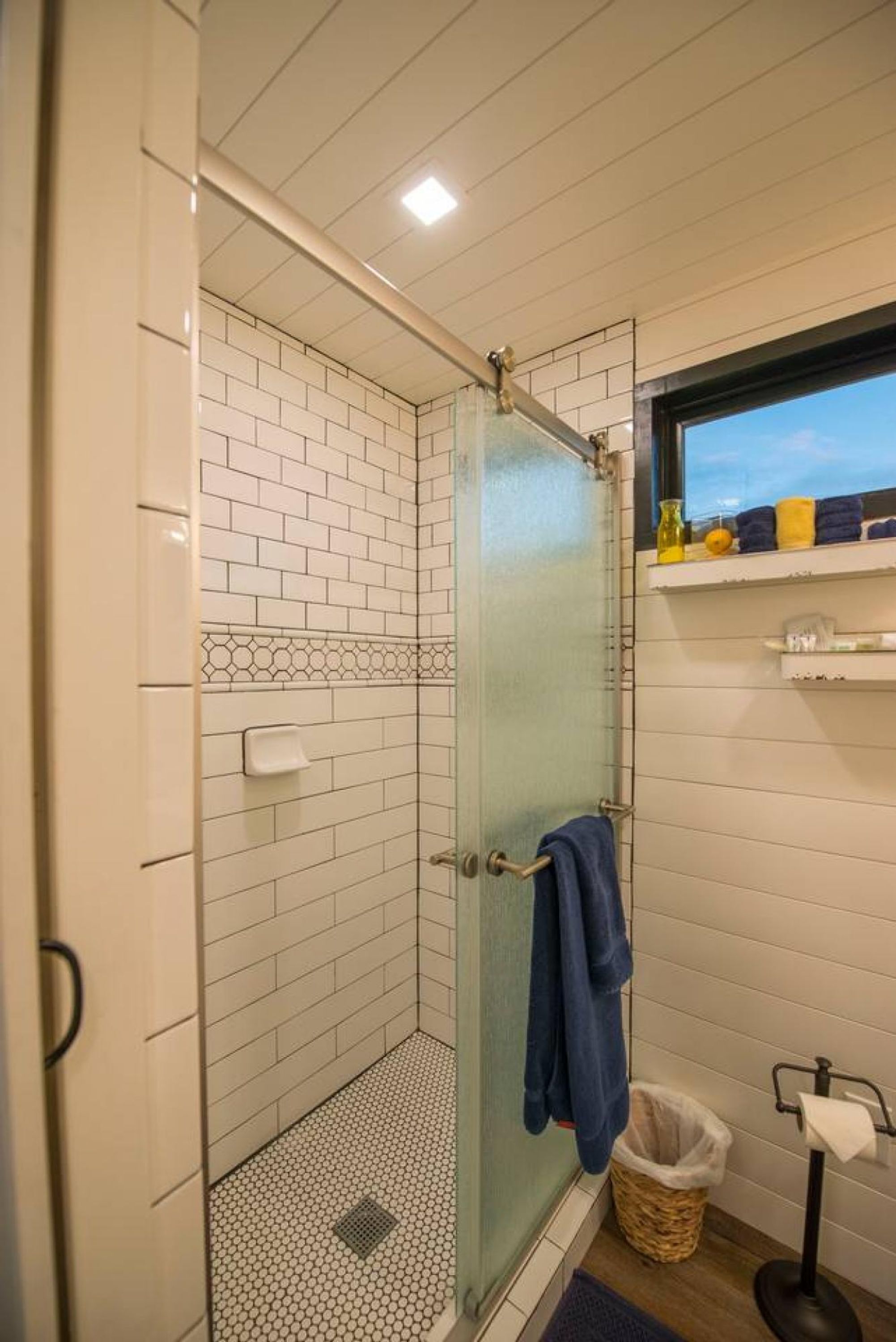Eine Dusche mit Glastür, ein Handtuchhalter und eine kleine Ablage mit Toilettenartikeln.