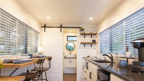 Une cuisine compacte avec des meubles blancs, un îlot central et un coin repas comprenant une table et des chaises.
