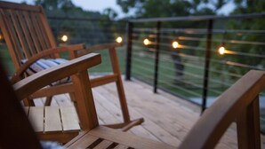 Une terrasse en bois avec deux chaises et une rambarde.