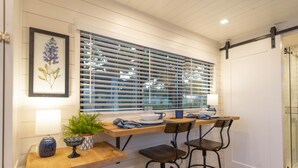 Une cuisine avec un plan de travail en bois, une fenêtre avec des stores et une porte.
