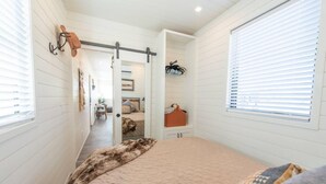 A bedroom with a bed, a door leading to another room, and a window with blinds. - New Longhorn Stunning Container Home-in Alpine (Alpine)