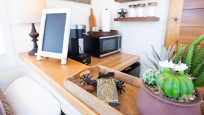 A wooden tray with a bicycle playing card game, a framed picture, a microwave, and a cactus plant on a kitchen counter. - New The Cowboy Boots-shipping Container Home (Alpine)