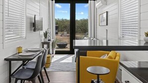 A modern kitchen with a dining area, featuring a kitchen island, bar stools, and a view through the window. - New The Yellow Beacon-luxury Shipping Container (Fredericksburg)