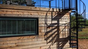 Een modern gebouw met een houten gevel, een groot raam en een spiltrap.
