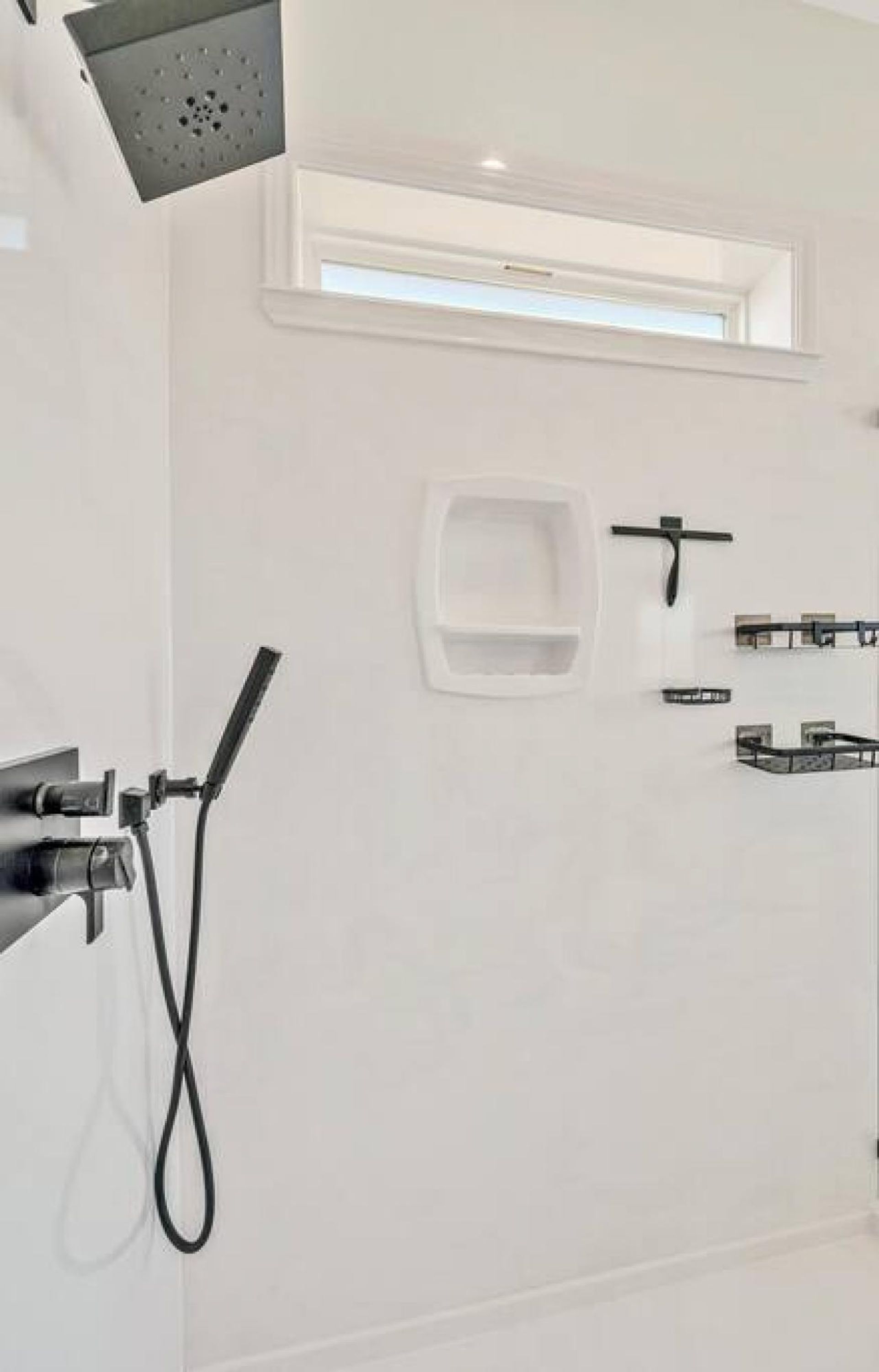 Ein modernes Badezimmer mit Dusche, kleinem Fenster und Handtuchhalter.