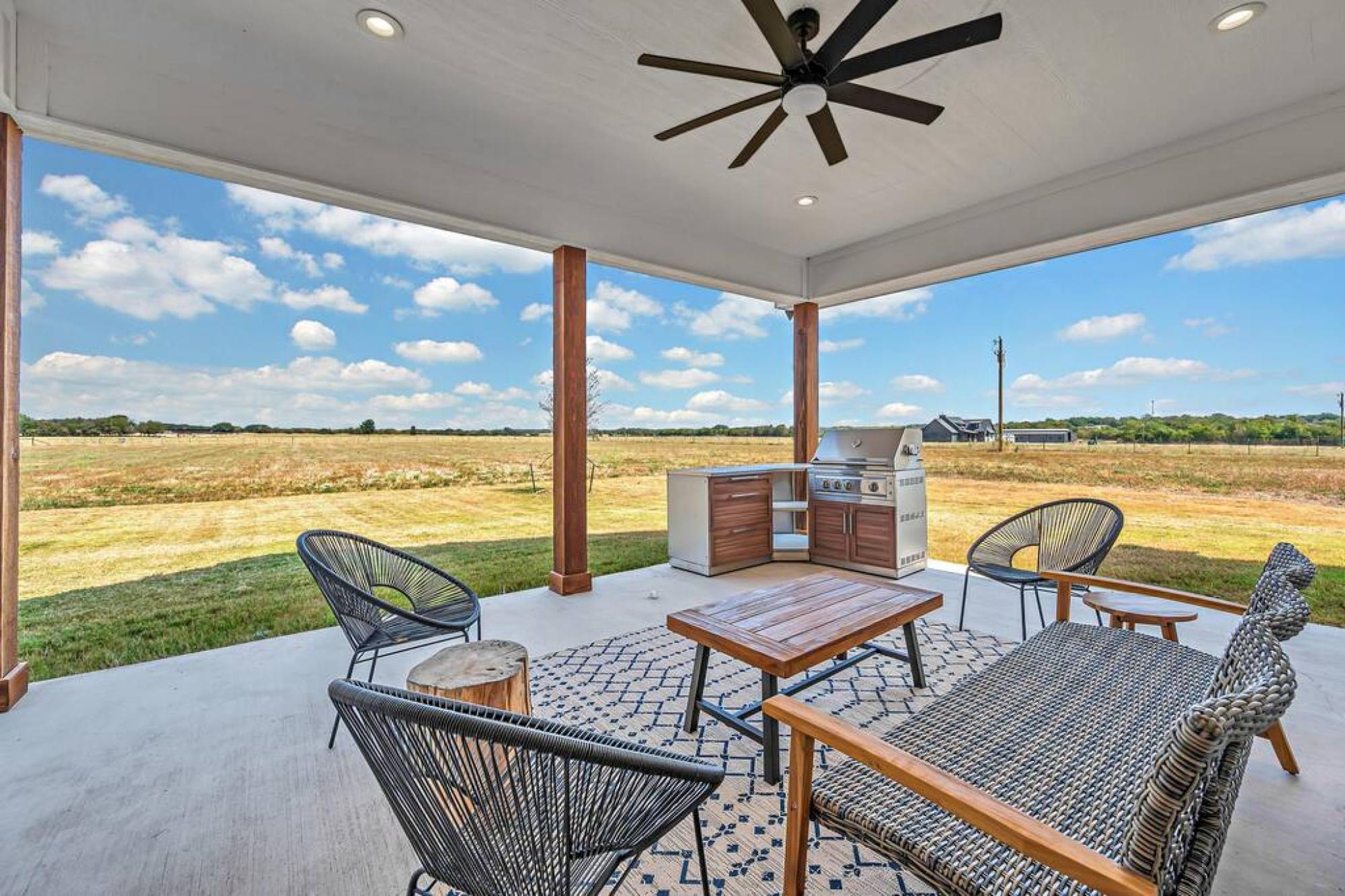 Eine Terrasse im Freien mit Grill, Sitzgelegenheiten und Blick auf die Landschaft.