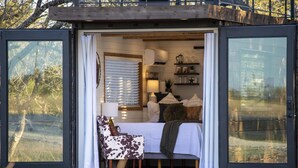 A cozy bedroom with a bed, pillows, a chair, and a lamp. - New The Lone Star Shipping Container (Fredericksburg)