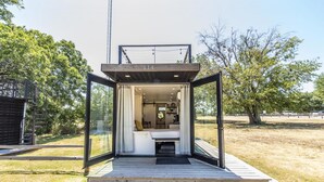 Interior moderno e espaçoso, com cozinha à vista, área de estar e escada que leva a um andar superior.