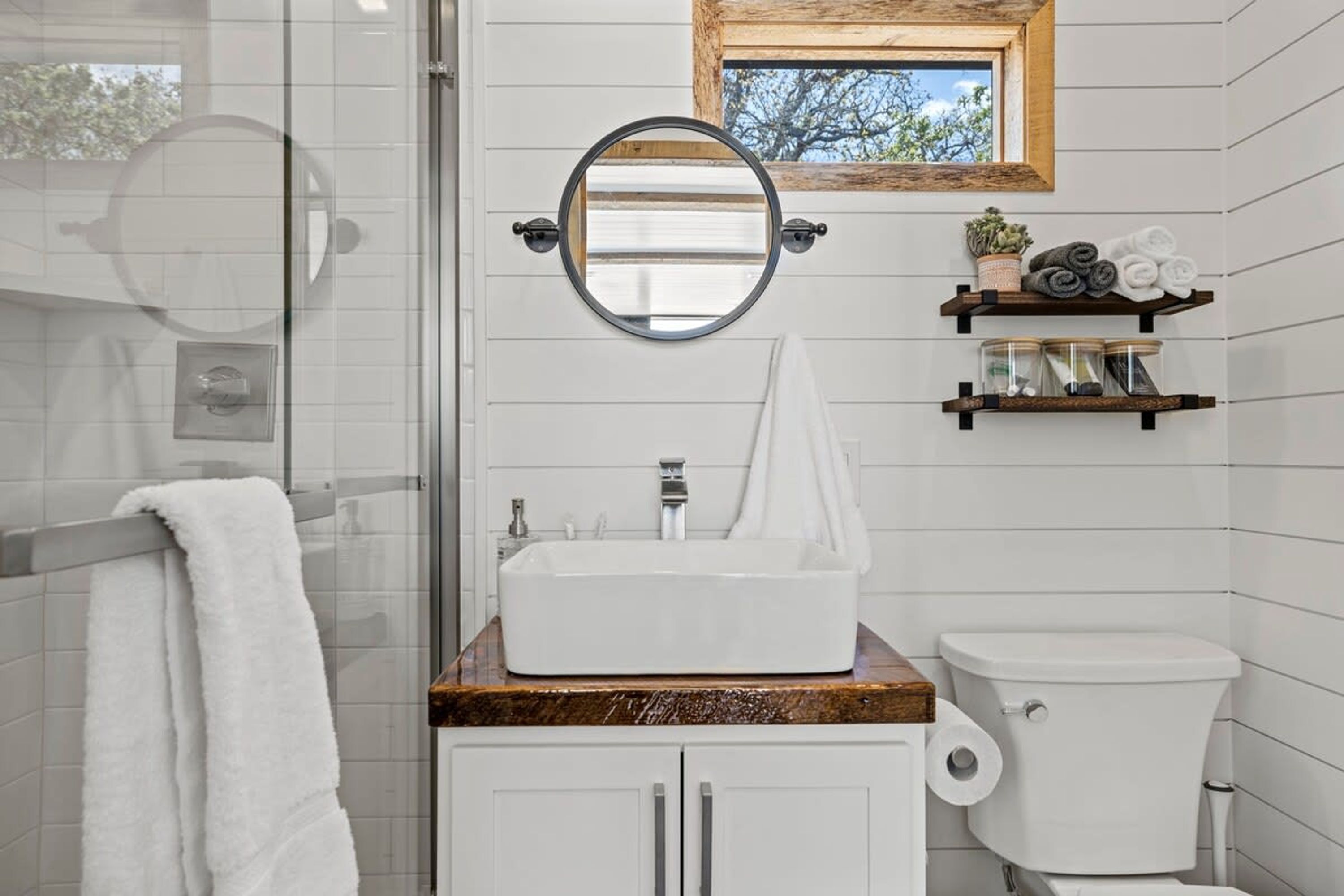 A bathroom with a white sink, a mirror, a toilet, and a shower area.