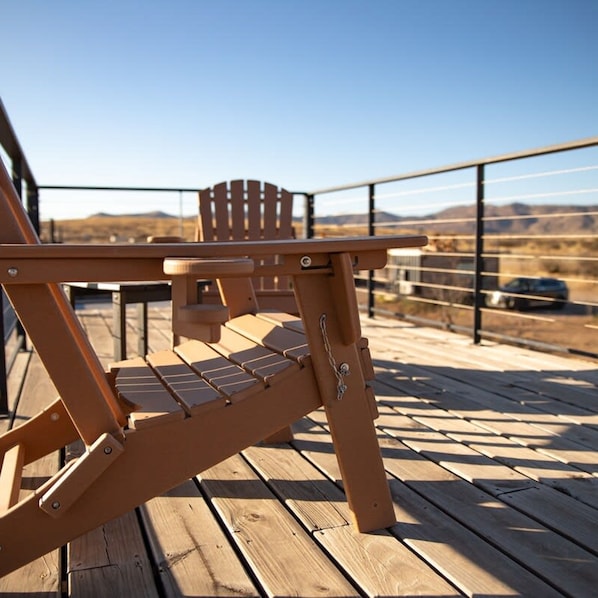 A wooden deck with a table and chairs, overlooking a mountainous landscape.