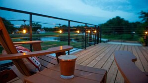 A wooden deck with a glass of beer, a chair, and a bench. - New Luxury Shipping Container (Waco)