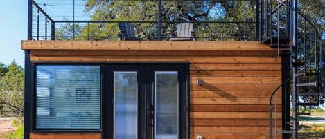 Una cabaña moderna con fachada de madera, ventanas amplias y un balcón.