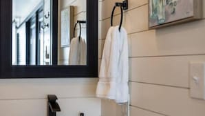 A modern bathroom with a large mirror, white sink, and a towel rack. - New Wilderness Hideout-cozy Container Home (Fredericksburg)