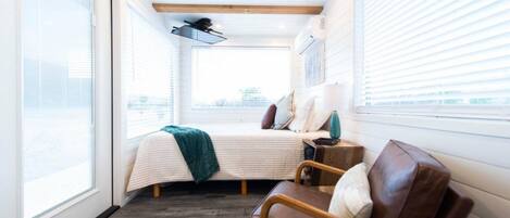 A bedroom with a bed, a window, a chair, and a nightstand.