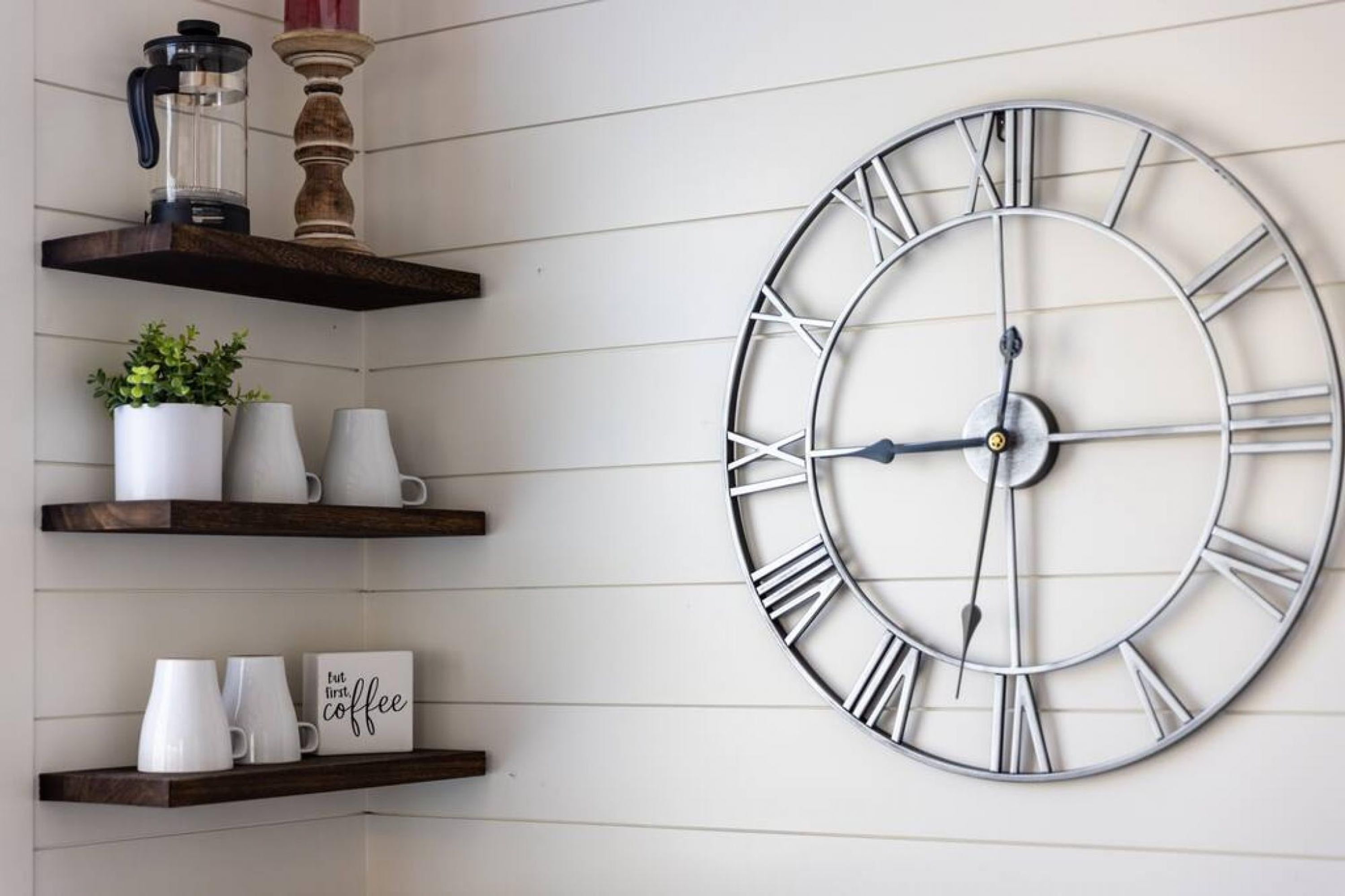 A wall clock with Roman numerals and a coffee-themed sign.