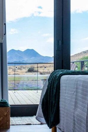Une chambre avec une grande fenêtre, un lit et une vue sur les montagnes.