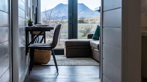 Una habitación con vistas a las montañas, una mesa con una silla y un sofá.