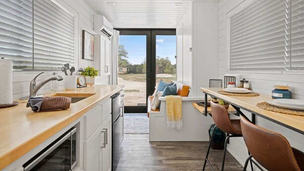 Une cuisine moderne dotée d’un îlot central, d’un évier et d’un coin repas avec des chaises.
