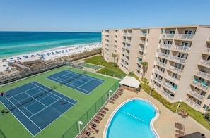 Un hotel con cancha de tenis, piscina y vista al mar.
