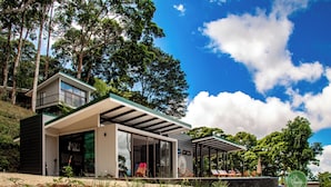 Une maison moderne dotée d’une façade en verre, d’un espace salon extérieur et d’une piscine.