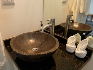 Une salle de bain avec un lavabo en granit, un miroir et un porte-serviettes avec des serviettes.