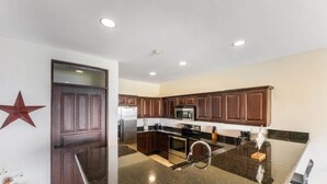 A modern kitchen with dark wooden cabinets, a stainless steel refrigerator, a microwave, and a black countertop. - Extraordinary 2br Condo in Ocotal with amazing Bay and Ocean Views!  (Coco)