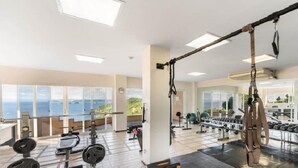 A gym with various exercise equipment, large windows, and a view of the sea. - Extraordinary 2br Condo in Ocotal with amazing Bay and Ocean Views!  (Coco)