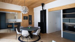 Una cocina moderna con techo de madera, un área de comedor con mesa y sillas redondas, y armarios empotrados negros.