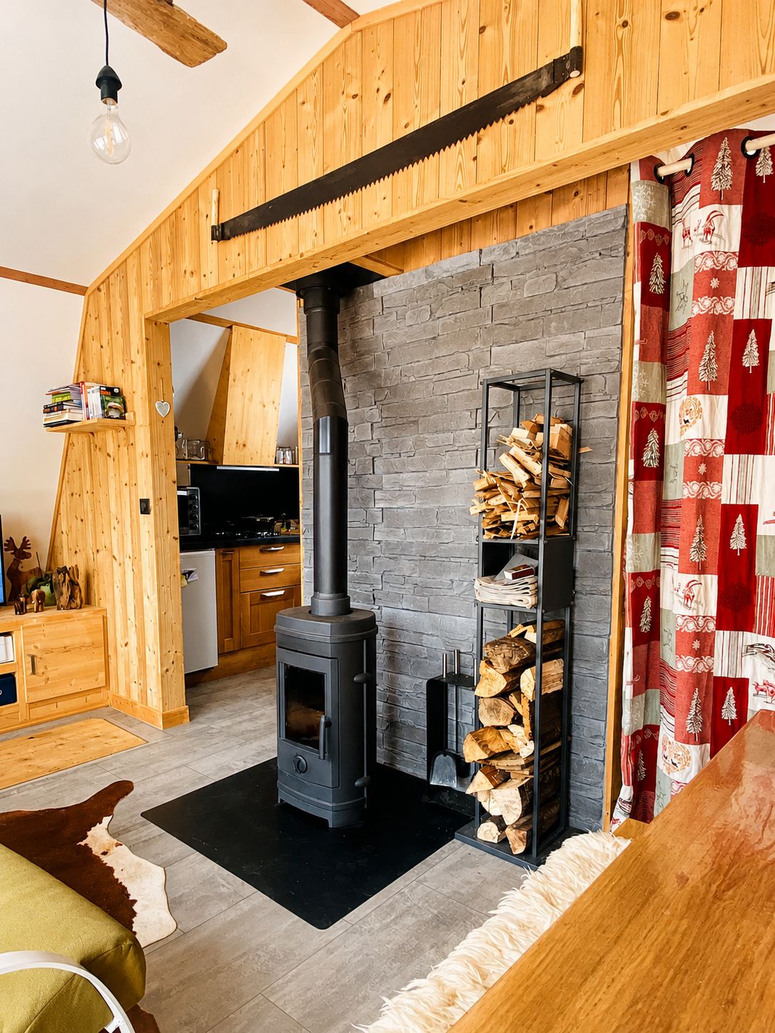 Ein gemütliches Wohnzimmer mit Kaminofen, Kamin und rustikaler Holzbalkendecke.