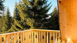 Une terrasse en bois avec une table de pique-nique, une bouteille de vin et un verre.