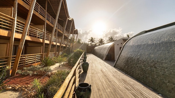 A wooden deck with a curved wall, a bamboo structure, and a clear sky. - Filho do Vento Kite Lodge (Canguaretama)
