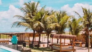 A swimming pool with lounge chairs and palm trees. - Filho do Vento Kite Lodge (Canguaretama)