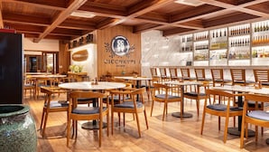 A restaurant interior with wooden furniture, a marble wall, and a bar area with bottles. - Filho do Vento Kite Lodge (Canguaretama)