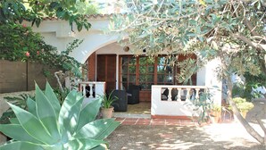 A patio area with a white railing, a seating area with chairs, and a large plant in the foreground. - SAONA VILLAS (VN MIANA): villa for 6 people, private swimming pool, air co (Les Tres Cales)
