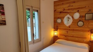 A bedroom with a wooden headboard, a bed with white bedding, a window with curtains, and wall-mounted mirrors and lights. - SAONA VILLAS (VN MIANA): villa for 6 people, private swimming pool, air co (Les Tres Cales)