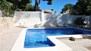 A rectangular swimming pool with a tiled edge, surrounded by stone tiles and white chairs. - SAONA VILLAS (VN MIANA): villa for 6 people, private swimming pool, air co (Les Tres Cales)