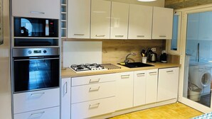 A modern kitchen with white cabinets, a built-in oven, a gas stove, and a sink. - SAONA VILLAS (VN MIANA): villa for 6 people, private swimming pool, air co (Les Tres Cales)
