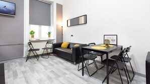 Un salon moderne comprenant un canapé, une table à manger, des chaises et un téléviseur fixé au mur.