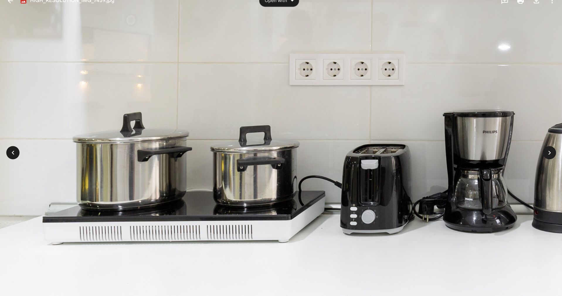 A kitchen with a stove, two pots, a toaster, a coffee maker, and a blender.