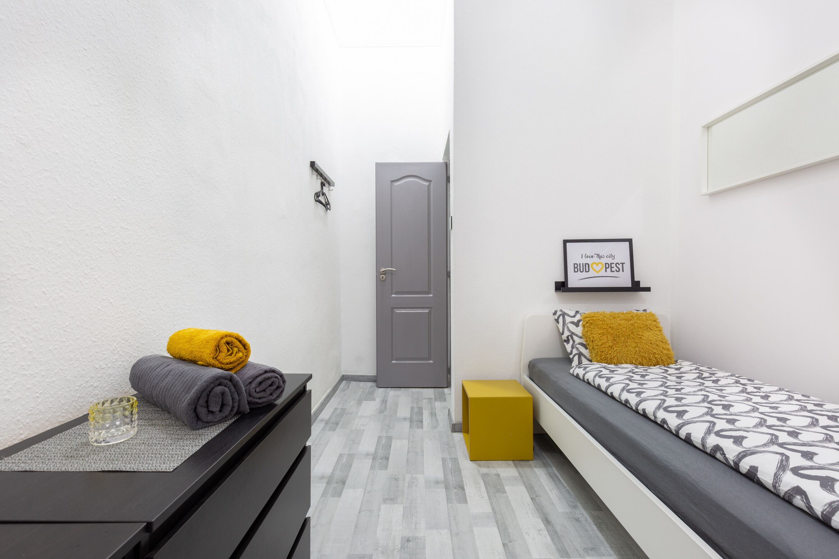 A small, modern room with a bed, a desk, and a door.
