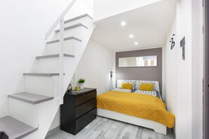 Un dormitorio con cama, cómoda, espejo e escalera.
