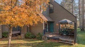A house with a porch, a table and chairs, and a large umbrella. - Perfect Location, Near Golf Course, SHARC passes (Sunriver)