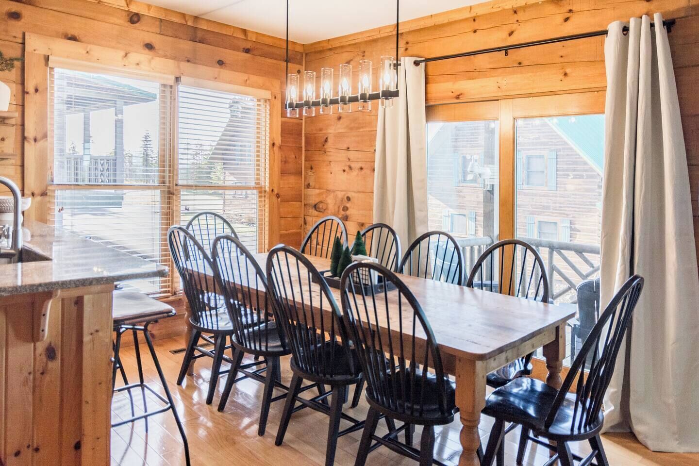 L’intérieur d’un chalet en bois, avec une table à manger, des chaises et un luminaire suspendu.
