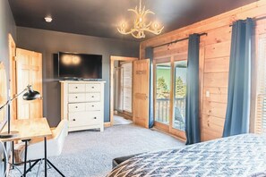 A bedroom with a bed, a TV, a dresser, and a chandelier.