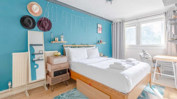 A neatly arranged bedroom with a bed, bedside tables, a desk, and a window with curtains. - Vibrant 1BD Flat - 8 Mins to Dalston, Hackney! (London)