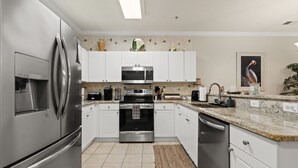 A modern kitchen with stainless steel appliances, white cabinets, and a granite countertop. - Willow Bend, Beautiful 2nd floor Villa  2Bedroom/2Bath, WiFi (North Myrtle Beach)