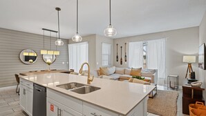 Une cuisine moderne dotée d’un îlot central, d’un lave-vaisselle encastré et de luminaires suspendus.